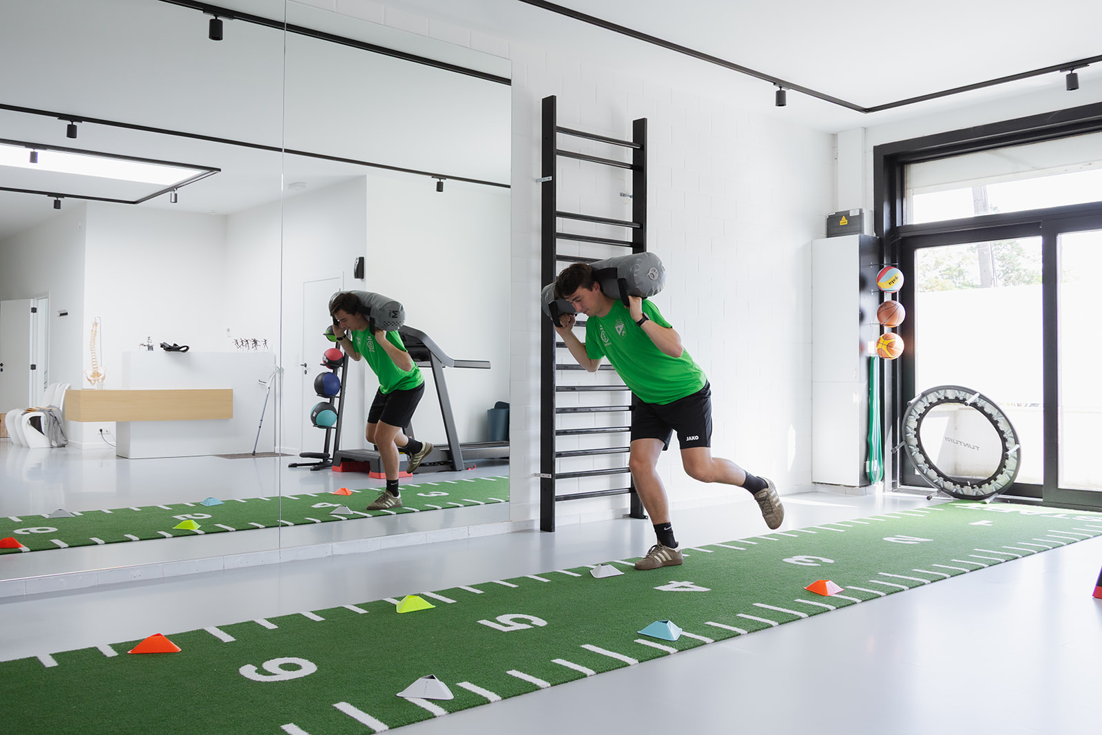 Sportkinesitherapie oefenruimte met kunstgras en revalidatietoestellen, balans- en krachttoestellen