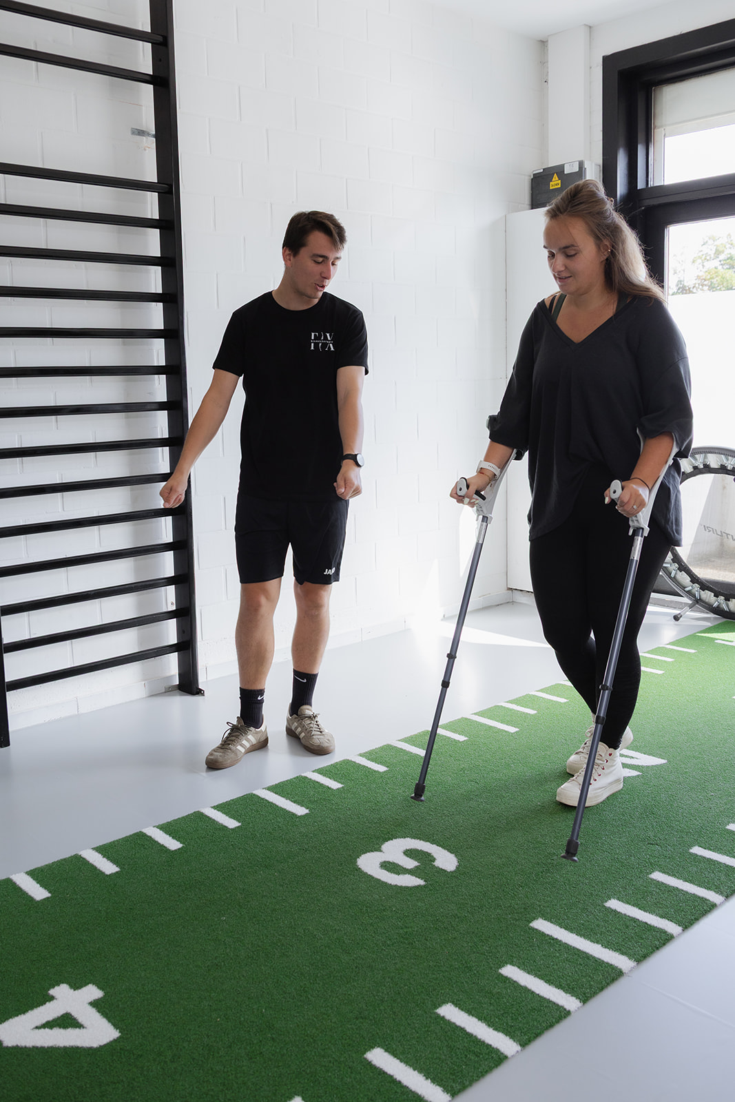 Kinesitherapeut begeleidt een patiënt met krukken tijdens orthopedische revalidatie